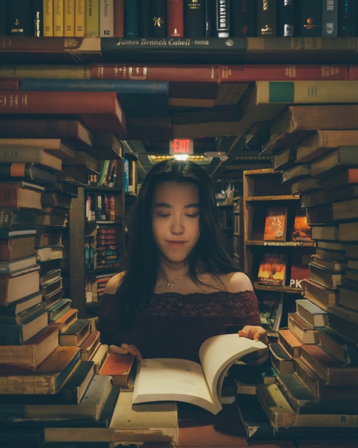 A woman enjoys reading in a cozy bookstore surrounded by countless books.